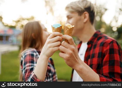 Love couple with ice cream in summer park, romantic youth. Young boyfriend and girl leisures with ice-cream together outdoor