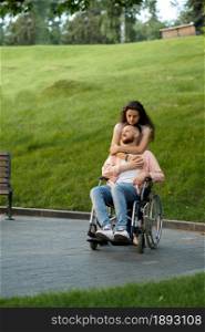 Love couple with wheelchair walking in autumn park. Paralyzed people and disability, care for a disabled woman. Smiling husband and wife overcome difficulties together. Love couple with wheelchair walking in autumn park