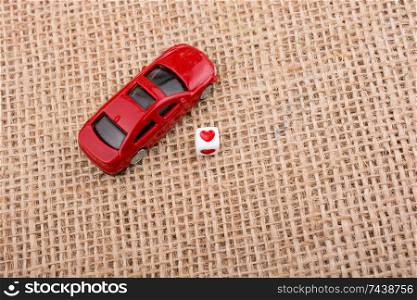 Love cube on a red toy car on a linen canvas