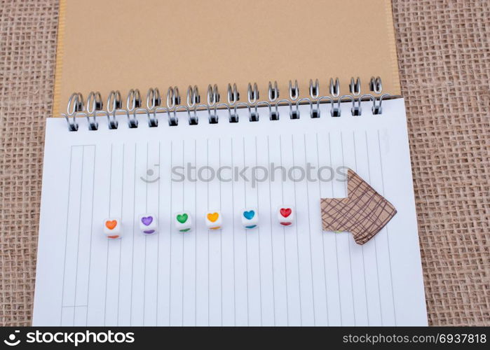 Love cubes and paper arrow on a notebook on canvas