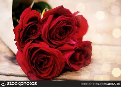 love, date, flowers, valentines day and holidays concept - close up of red roses bunch wrapped into brown paper on wooden table (vintage effect)
