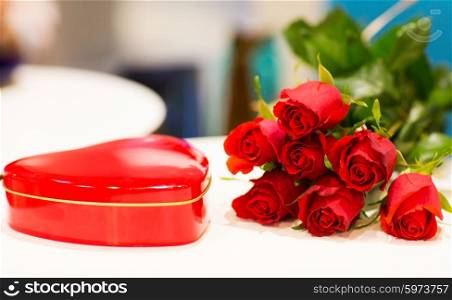 love, date, romance, valentines day and holidays concept - close up of red heart shaped chocolate box and rose flowers on table
