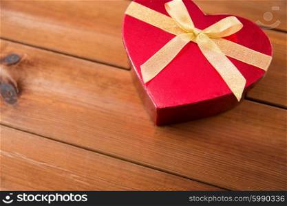 love, date, romance, valentines day and holidays concept - close up of heart shaped gift box on wood