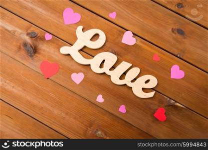 love, date, romance, valentines day and holidays concept - close up of word love with red and pink paper hearts on wood