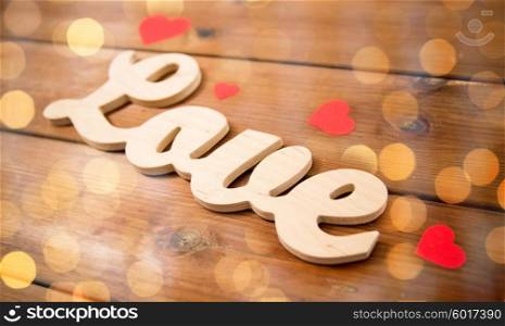 love, date, romance, valentines day and holidays concept - close up of word love with red paper hearts on wood