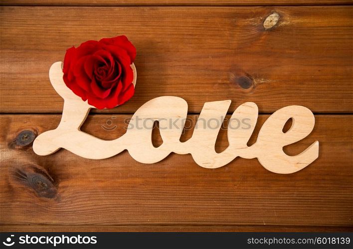 love, date, romance, valentines day and holidays concept - close up of word love cutout with red rose on wood