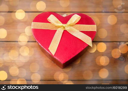 love, date, romance, valentines day and holidays concept - close up of heart shaped gift box on wood