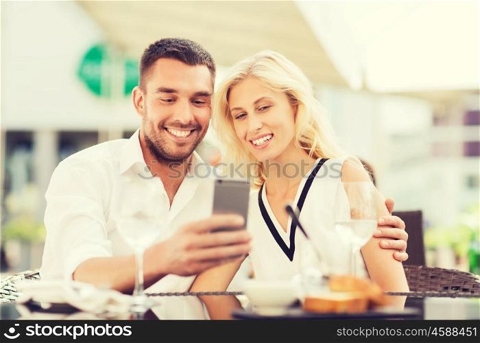 love, date, technology, people and relations concept - smiling happy couple taking selfie with smatphone at city street cafe