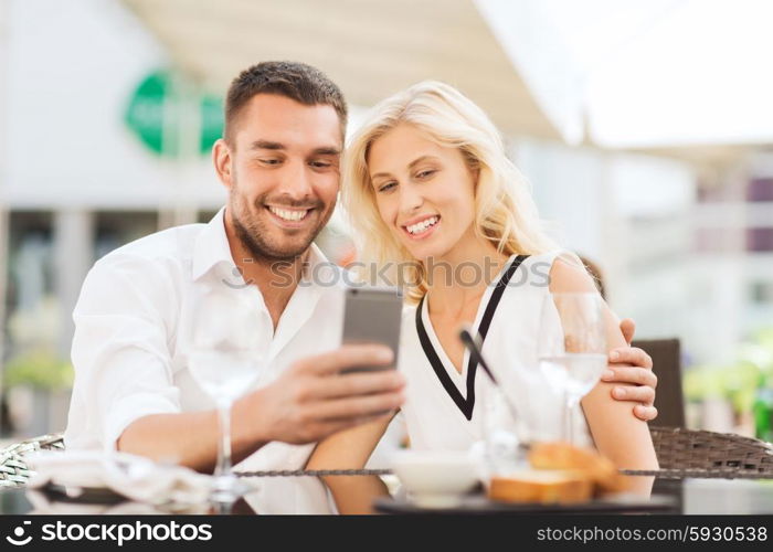 love, date, technology, people and relations concept - smiling happy couple taking selfie with smatphone at city street cafe