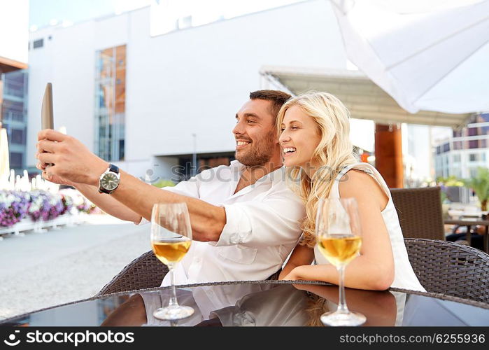 love, date, technology, people and relations concept - smiling happy couple taking selfie with tablet pc computer at restaurant terrace
