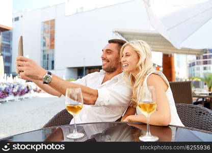 love, date, technology, people and relations concept - smiling happy couple taking selfie with tablet pc computer at restaurant terrace