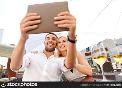 love, date, technology, people and relations concept - smiling happy couple taking selfie with tablet pc computer at restaurant terrace