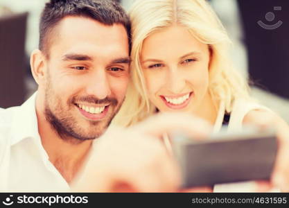 love, date, technology, people and relations concept - smiling happy couple taking selfie with smartphone outdoors