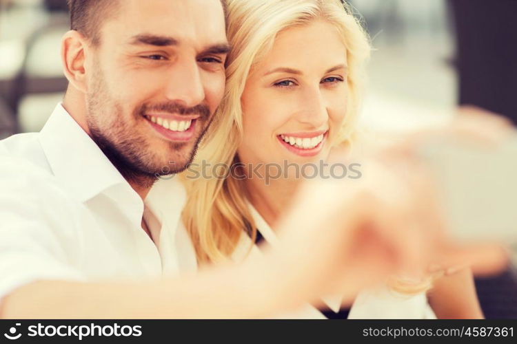 love, date, technology, people and relations concept - smiling happy couple taking selfie with smatphone outdoors