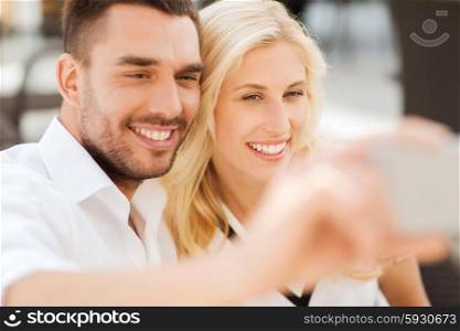 love, date, technology, people and relations concept - smiling happy couple taking selfie with smatphone outdoors