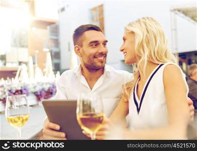 love, date, technology, people and relations concept - smiling happy couple with tablet pc computer at restaurant terrace
