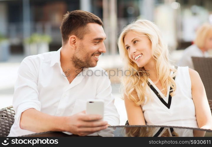 love, date, technology, people and relations concept - smiling happy couple with smatphone at city street cafe