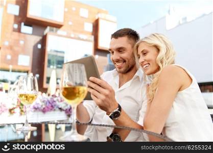 love, date, technology, people and relations concept - smiling happy couple with tablet pc computer at restaurant terrace