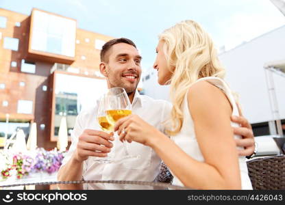 love, dating, people and holidays concept - happy couple drinking wine at open-air restaurant and clinking glasses