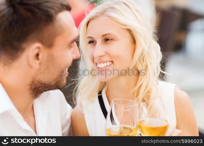 love, dating, people and holidays concept - smiling couple clinking glasses of wine and looking to each other at restaurant lounge or terrace