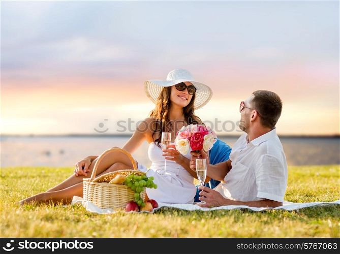 love, dating, people and holidays concept - smiling couple drinking champagne on picnic over evening seaside background