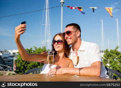 love, dating, people and holidays concept - smiling couple wearing sunglasses drinking champagne and making selfie at cafe