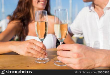 love, dating, people and holidays concept - smiling couple wearing sunglasses drinking champagne and looking to each other at cafe