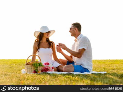 love, dating, people and holidays concept - smiling young man showing small red gift box to his girlfriend on picnic