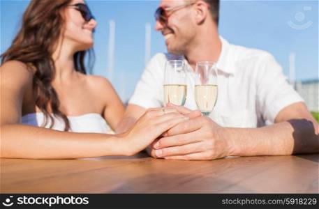 love, dating, wedding, people and holidays concept - happy just married couple in sunglasses with wedding ring and champagne and glasses looking to each other at cafe