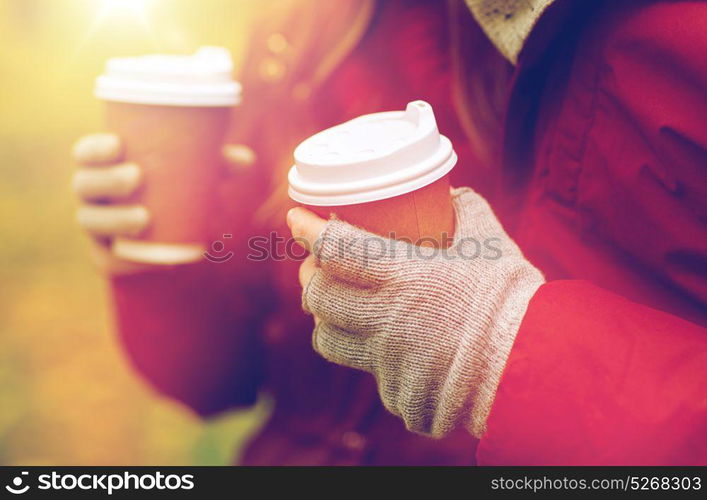 love, drinks and people concept - close up of couple hands with coffee cups in autumn park. close up of couple hands with coffee in autumn