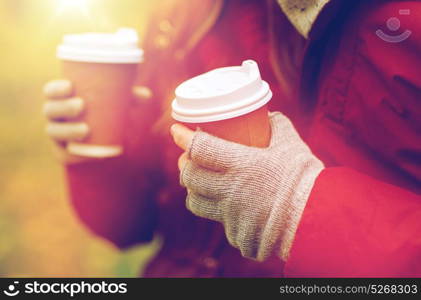 love, drinks and people concept - close up of couple hands with coffee cups in autumn park. close up of couple hands with coffee in autumn