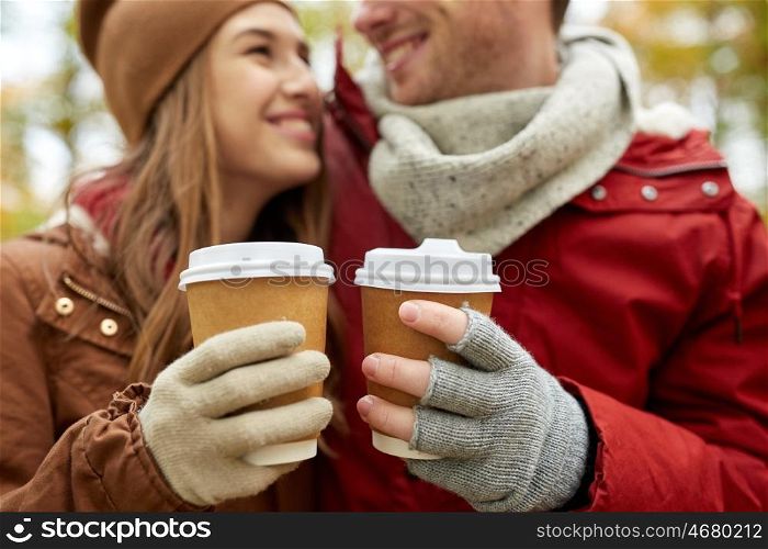 love, drinks and people concept - close up of happy young couple with coffee cups in autumn park