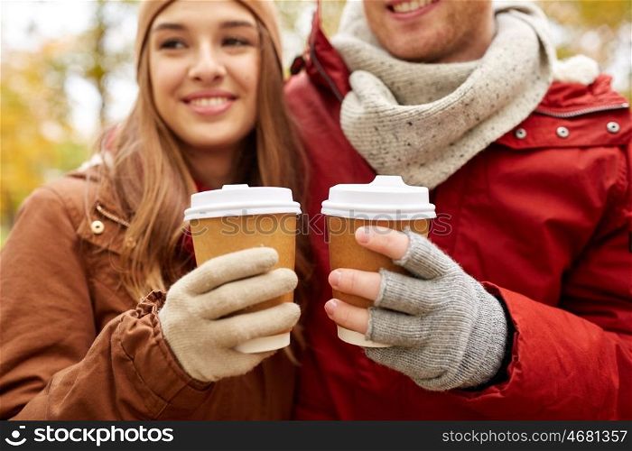 love, drinks and people concept - close up of happy young couple with coffee cups in autumn park