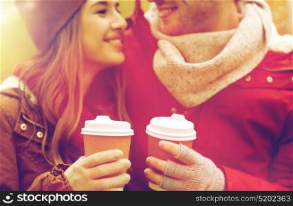 love, drinks and people concept - close up of happy young couple with coffee cups in autumn park. close up of happy couple with coffee in autumn