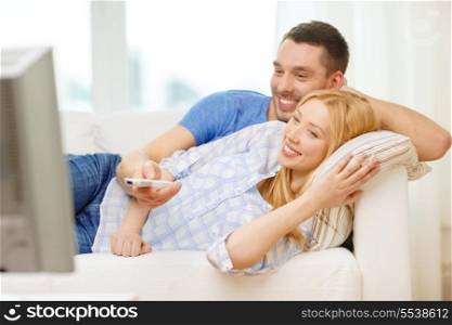 love, family and happiness concept - smiling couple watching movie at home