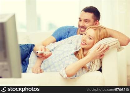 love, family and happiness concept - smiling couple watching movie at home