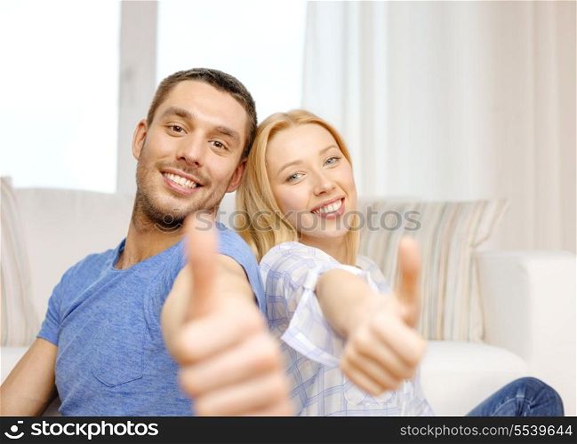 love, family and happiness concept - smiling happy couple at home showing thumbs up