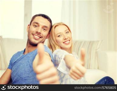 love, family and happiness concept - smiling happy couple at home showing thumbs up