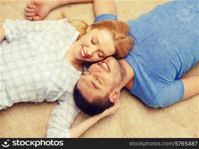 love, family and happiness concept - smiling happy couple lying on floor at home