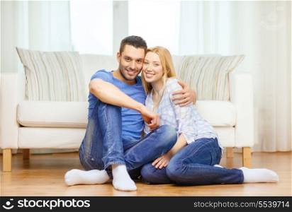 love, family and happiness concept - smiling happy couple sitting on floor at home