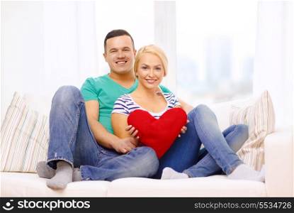 love, family and happiness concept - smiling happy couple with red heart at home