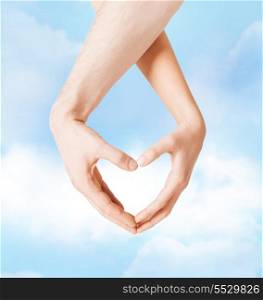 love, family and relationships concept - closeup of woman and man hands showing heart shape