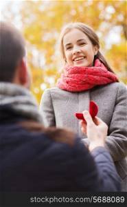 love, family, autumn and people concept - close up of smiling couple with engagement ring in small red gift box outdoors