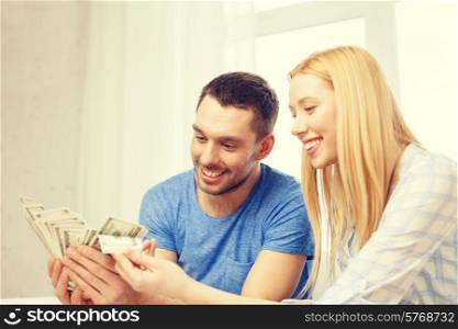 love, family, finance, money and happiness concpet - smiling couple with money at home