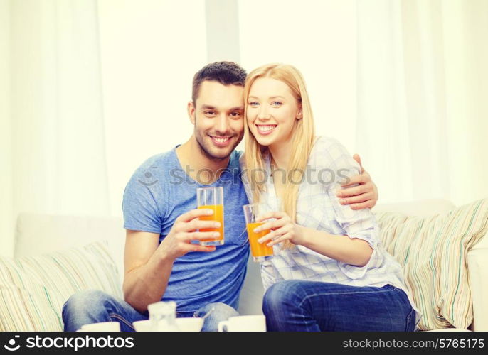 love, family, healthy food and happiness concept - smiling happy couple drinking juice at home
