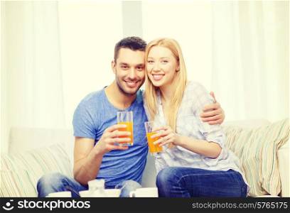 love, family, healthy food and happiness concept - smiling happy couple drinking juice at home