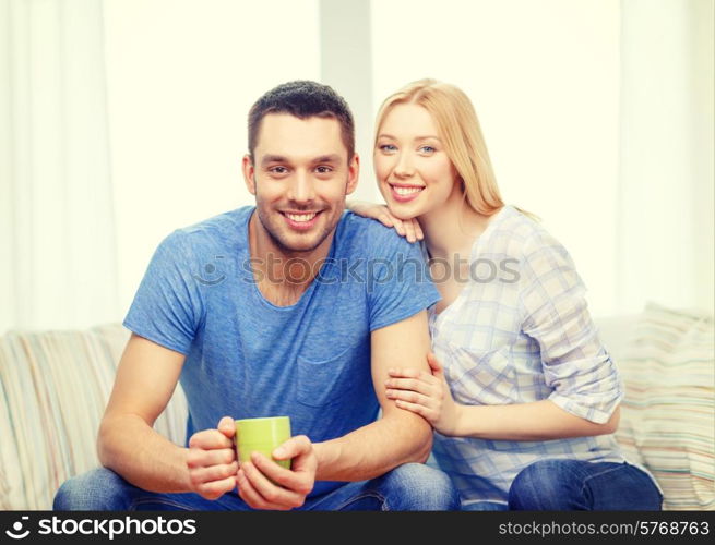 love, family, healthy food and happiness concept - smiling man with cup of tea or coffee with wife or girlfriend at home