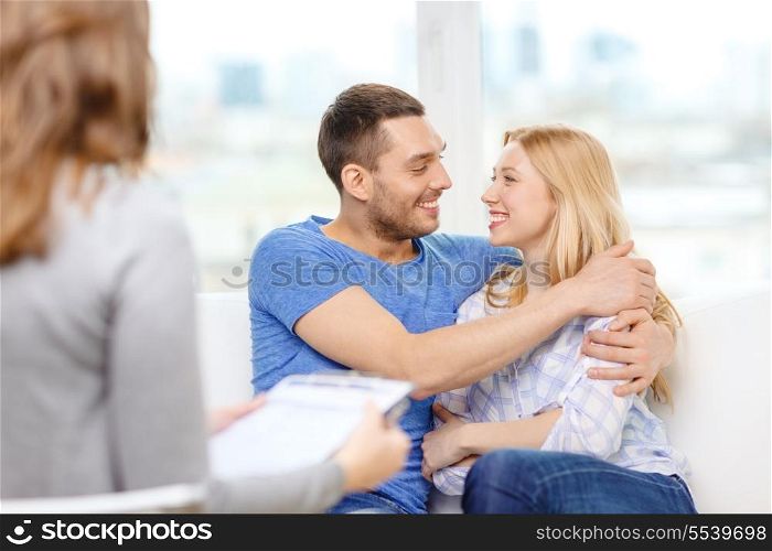 love, family, phychology and happiness concept - young couple hugging at psychologist office