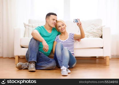 love, family, technology and happiness concept - smiling couple taking self portrait picture with digital camera at home