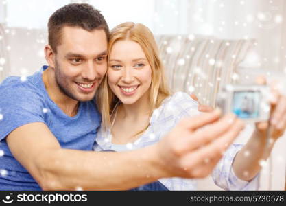 love, family, technology and happiness concept - smiling couple taking self portrait picture with digital camera at home